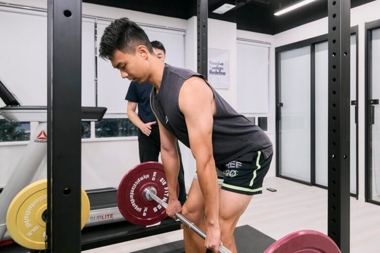 Patient performing a weighted deadlift to rebuild lumbar strength and redefine long-term athletic performance.